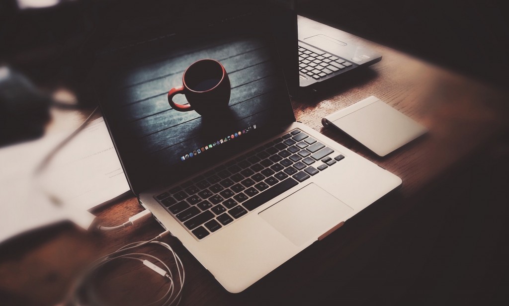 Bild von Laptop auf Schreibtisch mit Kaffeetasse auf dem Bildschirm